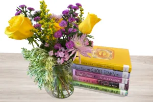 Flowers in a vase next to a stack of books.