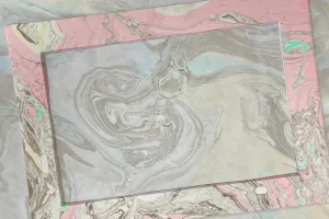 Paper marbled with light pink and black ink.