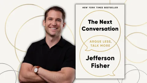 Man in black polo shirt next to his book.