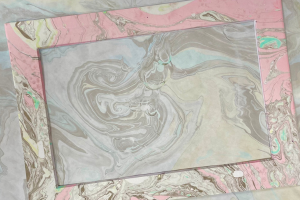 Paper marbled with light pink and black ink.